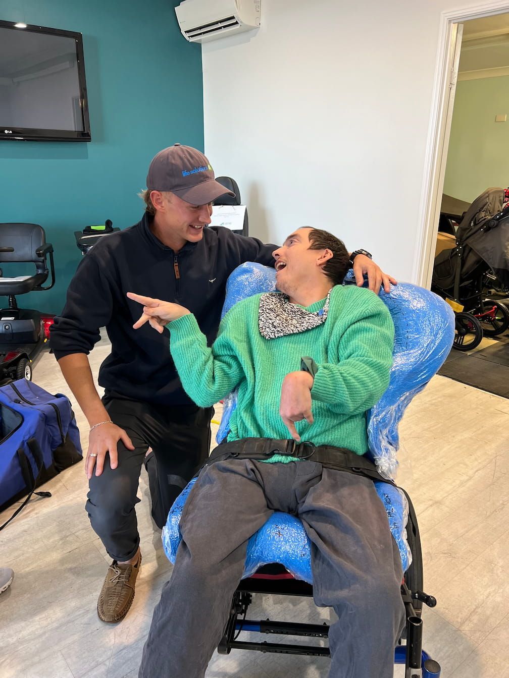 A Victor Harbor occupational therapist is sitting next to a man in a wheelchair.