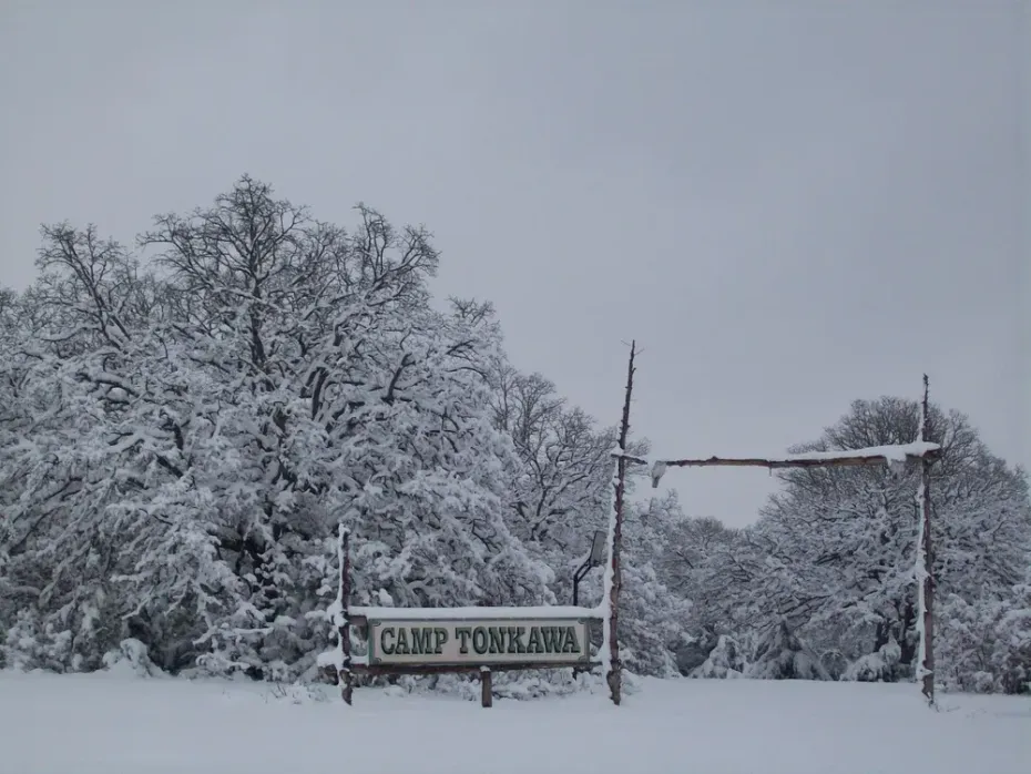 Snowy roadside entrance with a sign reading “Camp Honesa”