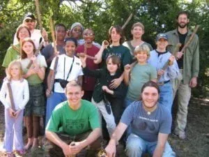Group of people posing outdoors in a garden, smiling with trees in the background.