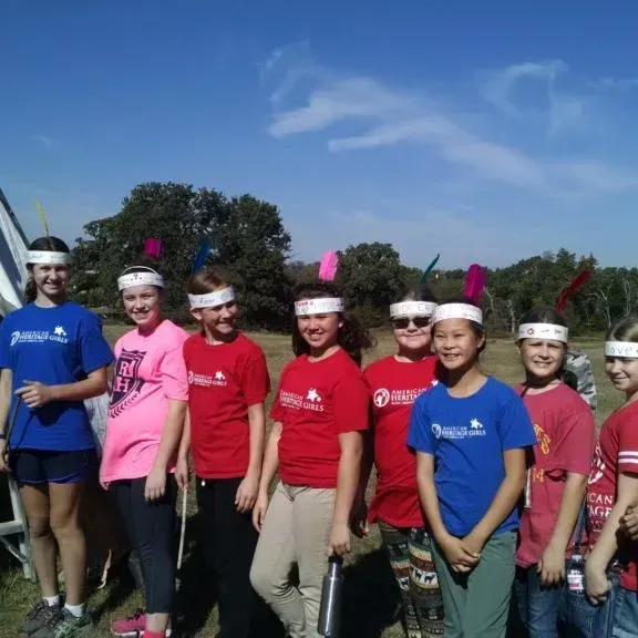 Group of people in red and blue shirts wearing headbands, standing outdoors under a sunny sky.