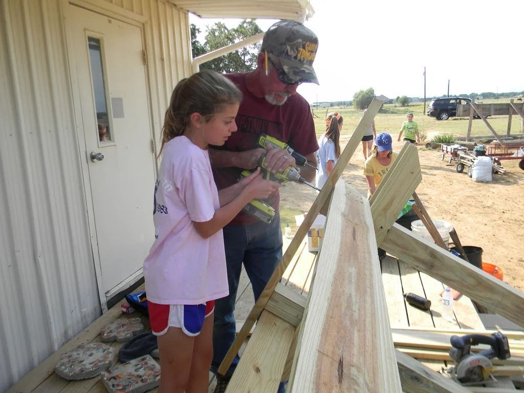 Two people working together on a wooden structure beside a building at a construction site