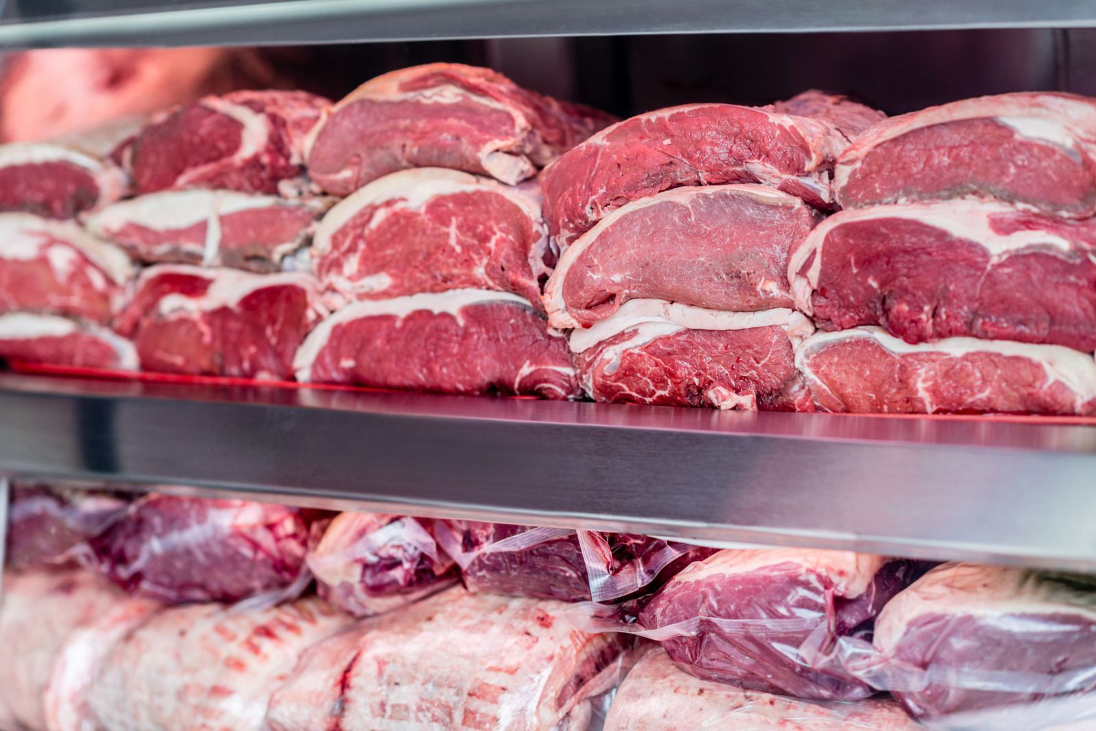 Rows of raw steaks displayed on a butcher’s refrigerated shelf