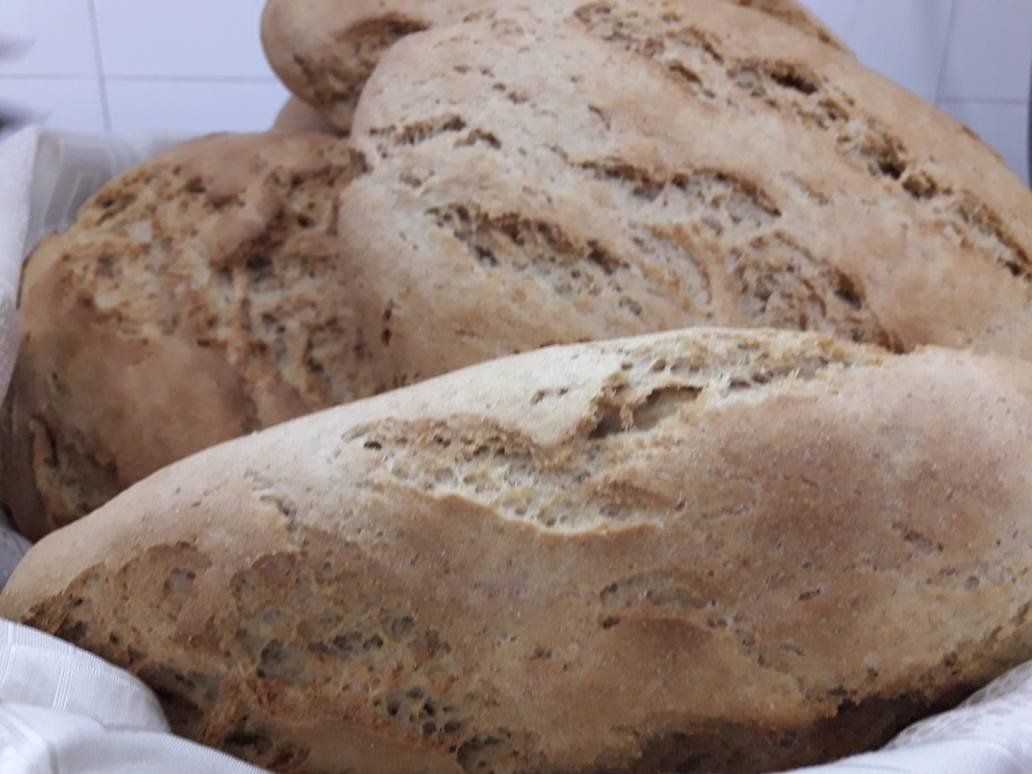 Pagnotte di pane rustico, dorato, in un cestino foderato di bianco.