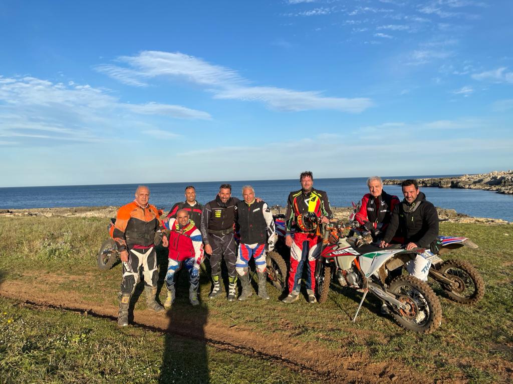 Un gruppo di motociclisti in tenuta da motociclista posa in riva al mare.