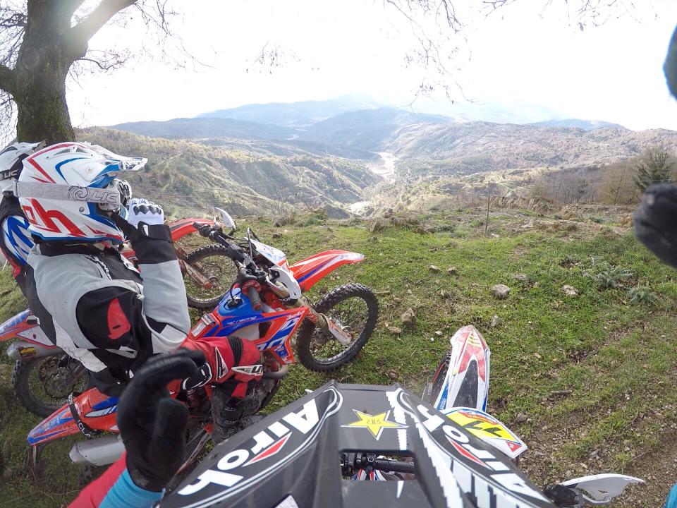 Due motociclisti in tenuta da motociclista che si affacciano su una valle di montagna.