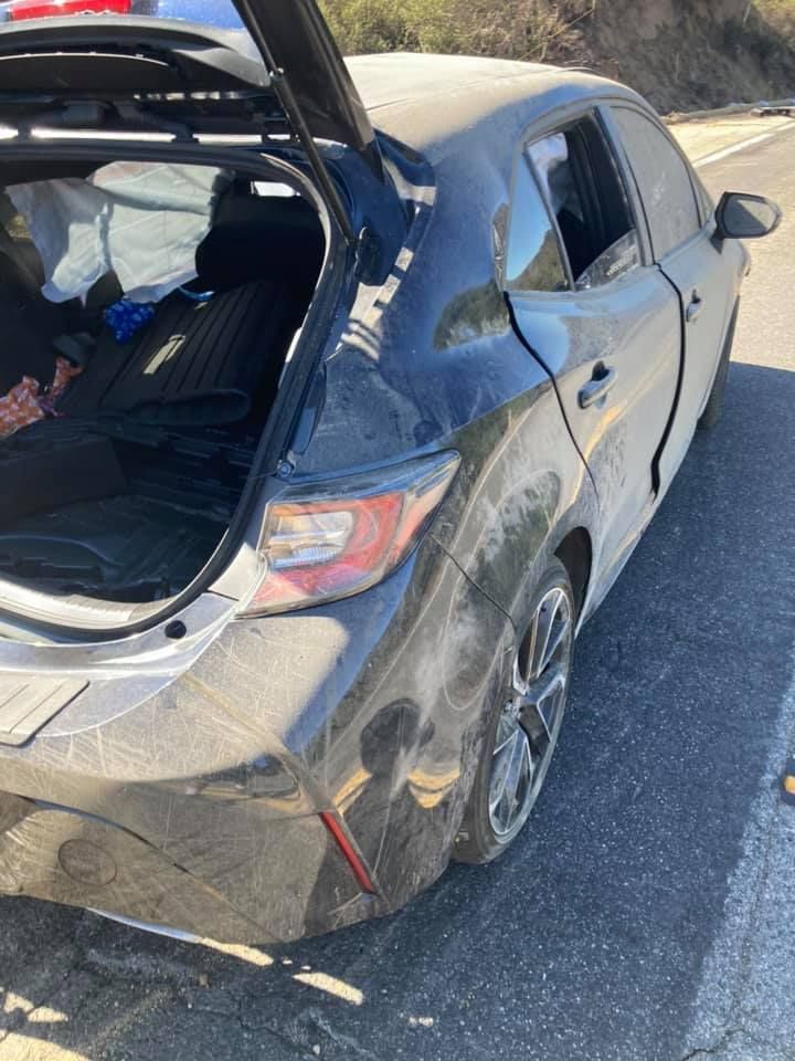 Black car, rear hatch open, parked on road. Dirt on exterior.
