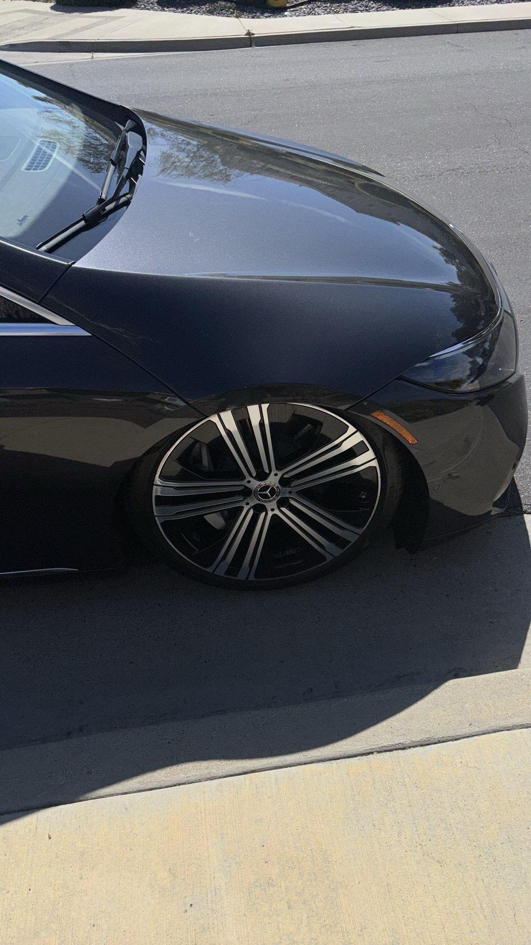 Black car with custom black and silver rims, lowered, parked on pavement.
