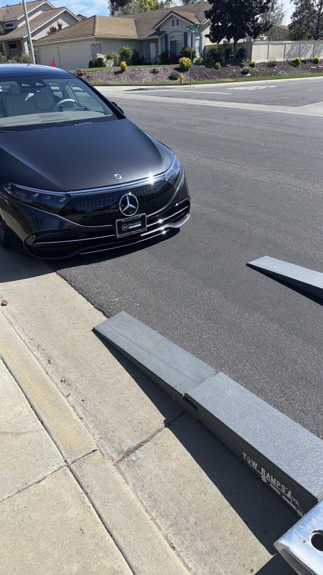 Black Mercedes-Benz car parked on a street, with two ramps in front.