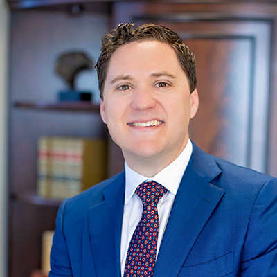 Smiling professional in a blue suit and patterned tie in an office setting