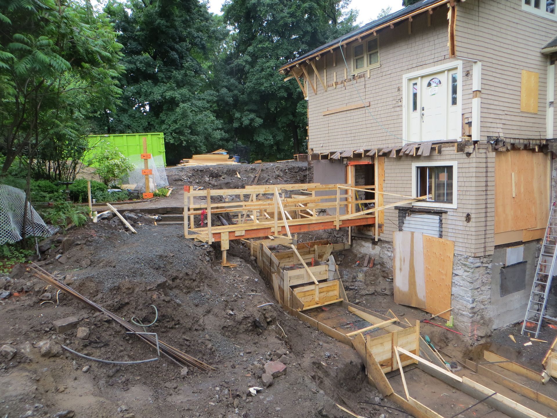House under construction, with wooden scaffolding, dirt, and unfinished structure.
