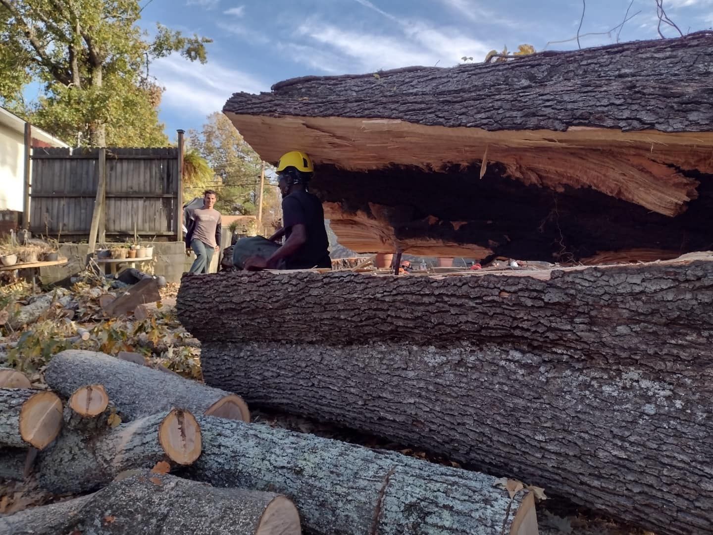 A man is standing on top of a pile of logs.