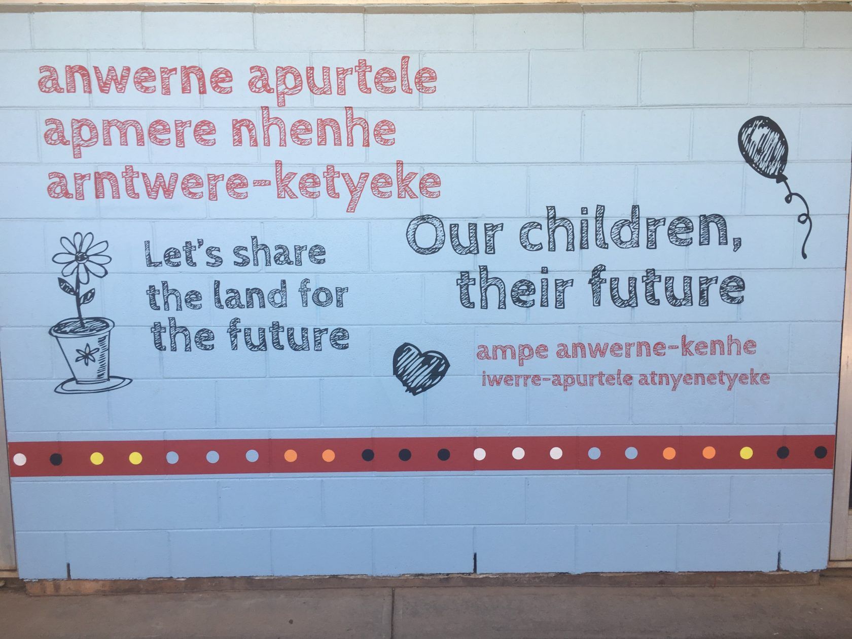 Mural: Text in native language and English. Includes a flower, balloon, heart, and the phrase 