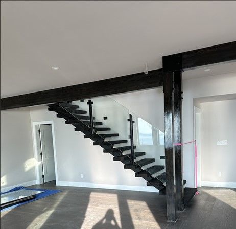 Interior room with black metal staircase and beam against white walls and gray floor.
