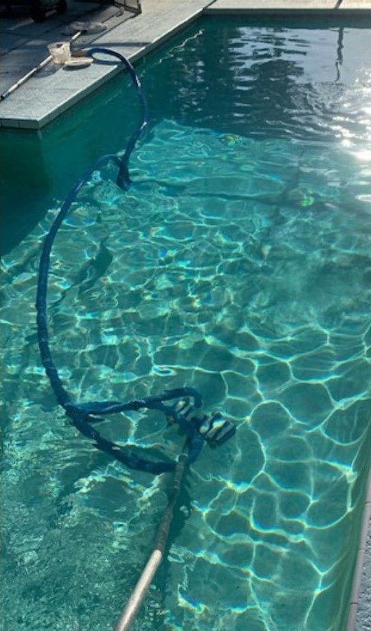 A hose is attached to the side of a swimming pool.