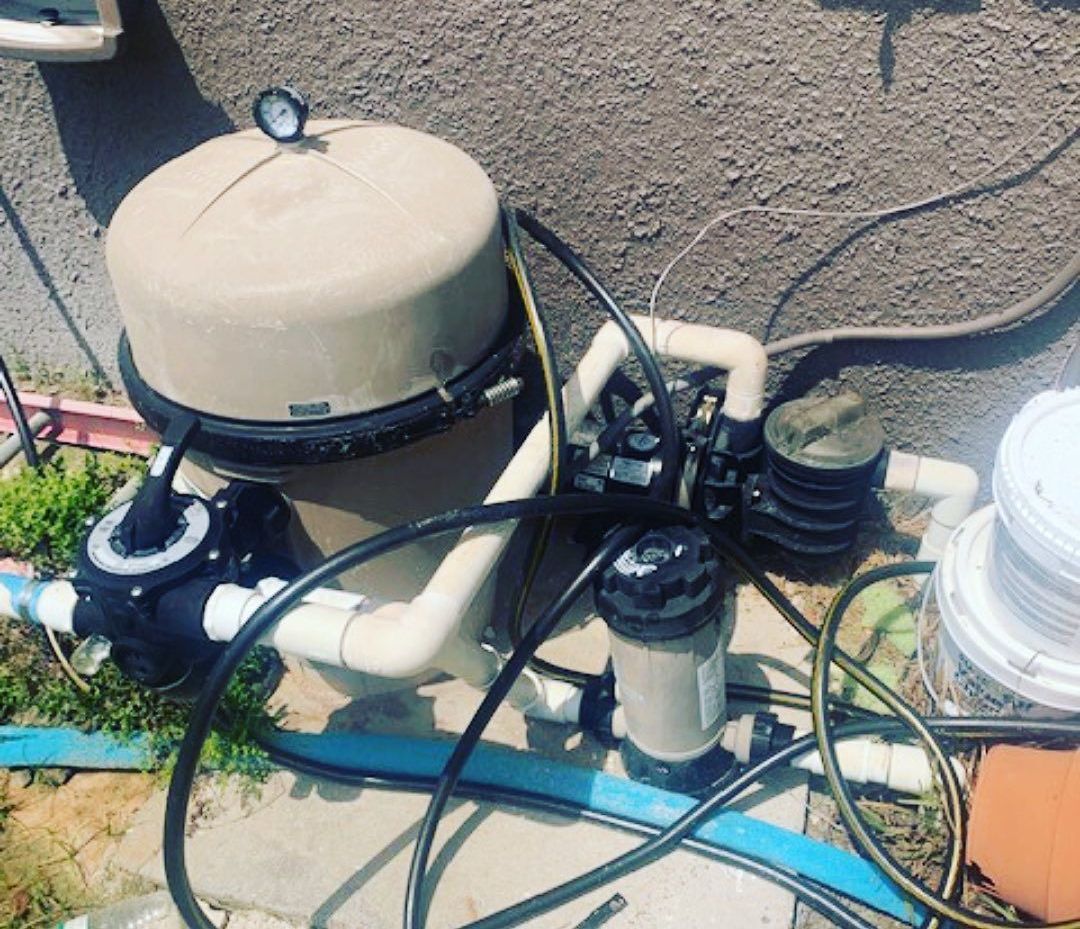 A swimming pool filter is sitting on a sidewalk next to a wall.