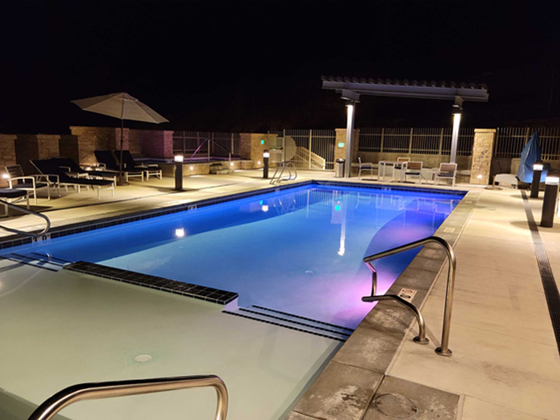 A large swimming pool is lit up at night.