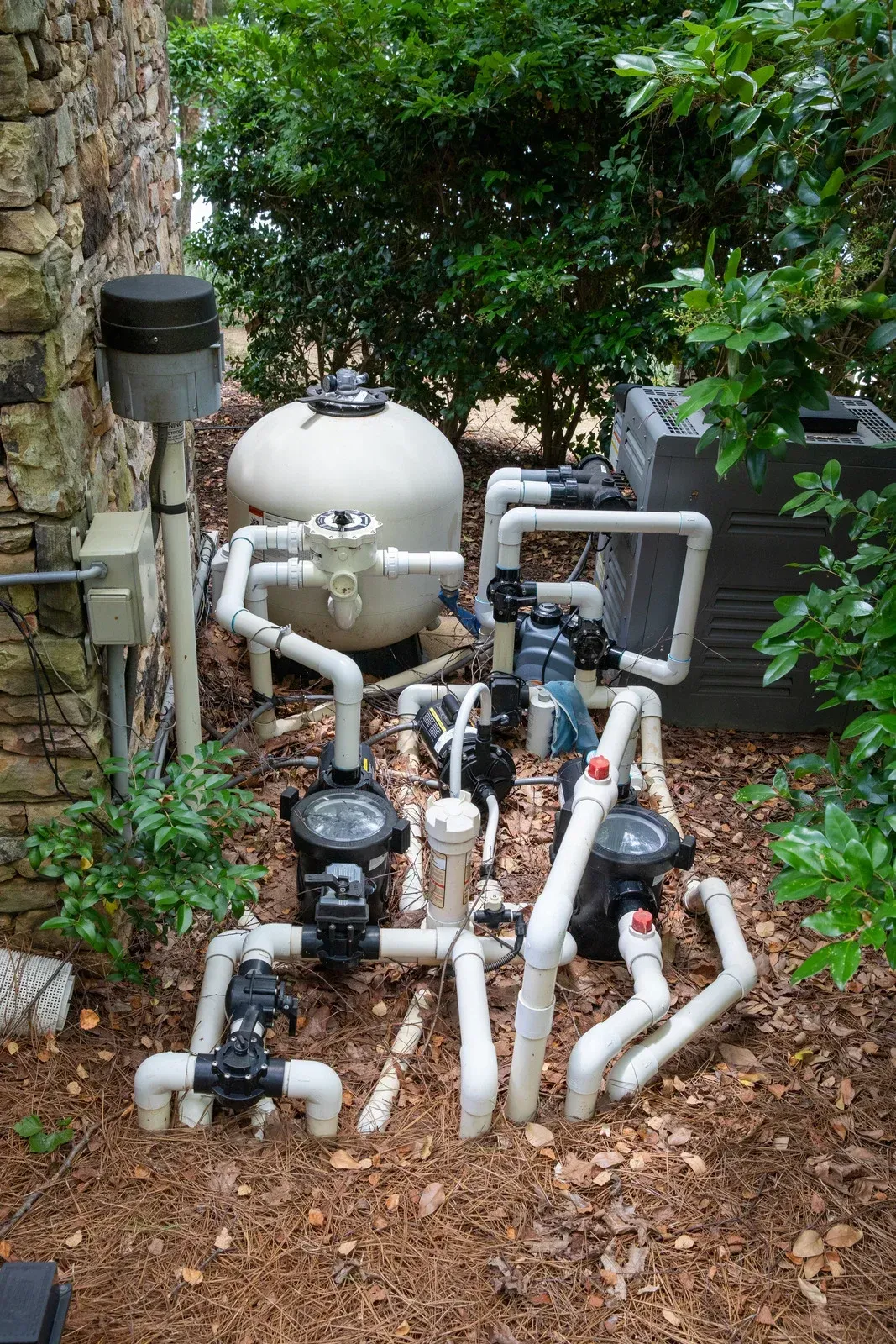 A bunch of pipes are sitting on the ground next to a swimming pool.