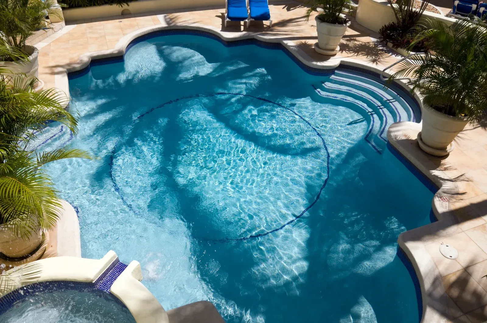 A person is holding a thermometer in front of a swimming pool.