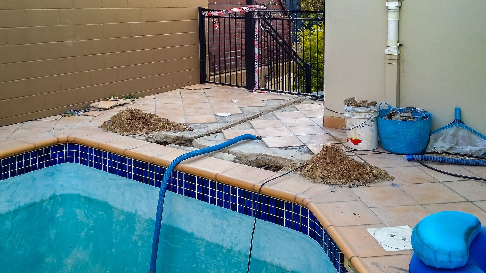 A swimming pool is being remodeled with a blue hose