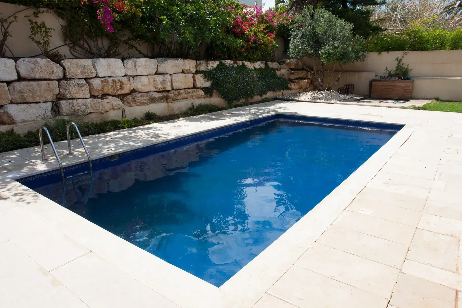 A large swimming pool with a stone wall in the background
