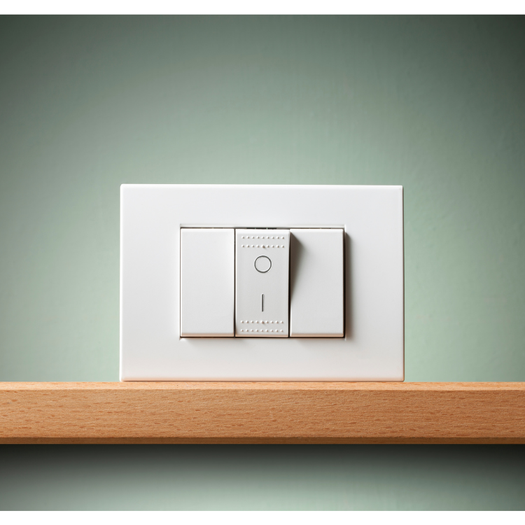 A white light switch is sitting on a wooden shelf.