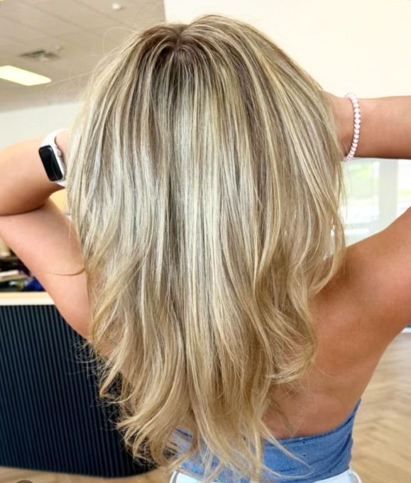 Blonde hair with highlights, layered and wavy, seen from the back.