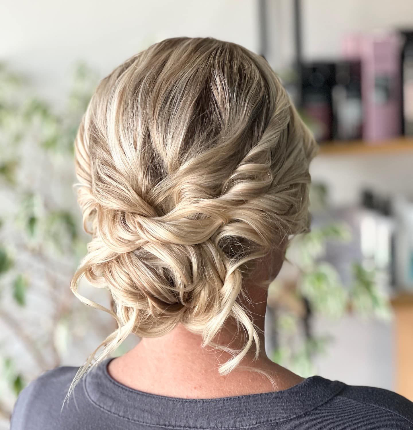 Blonde updo hairstyle with twisted sections, against a blurred background.
