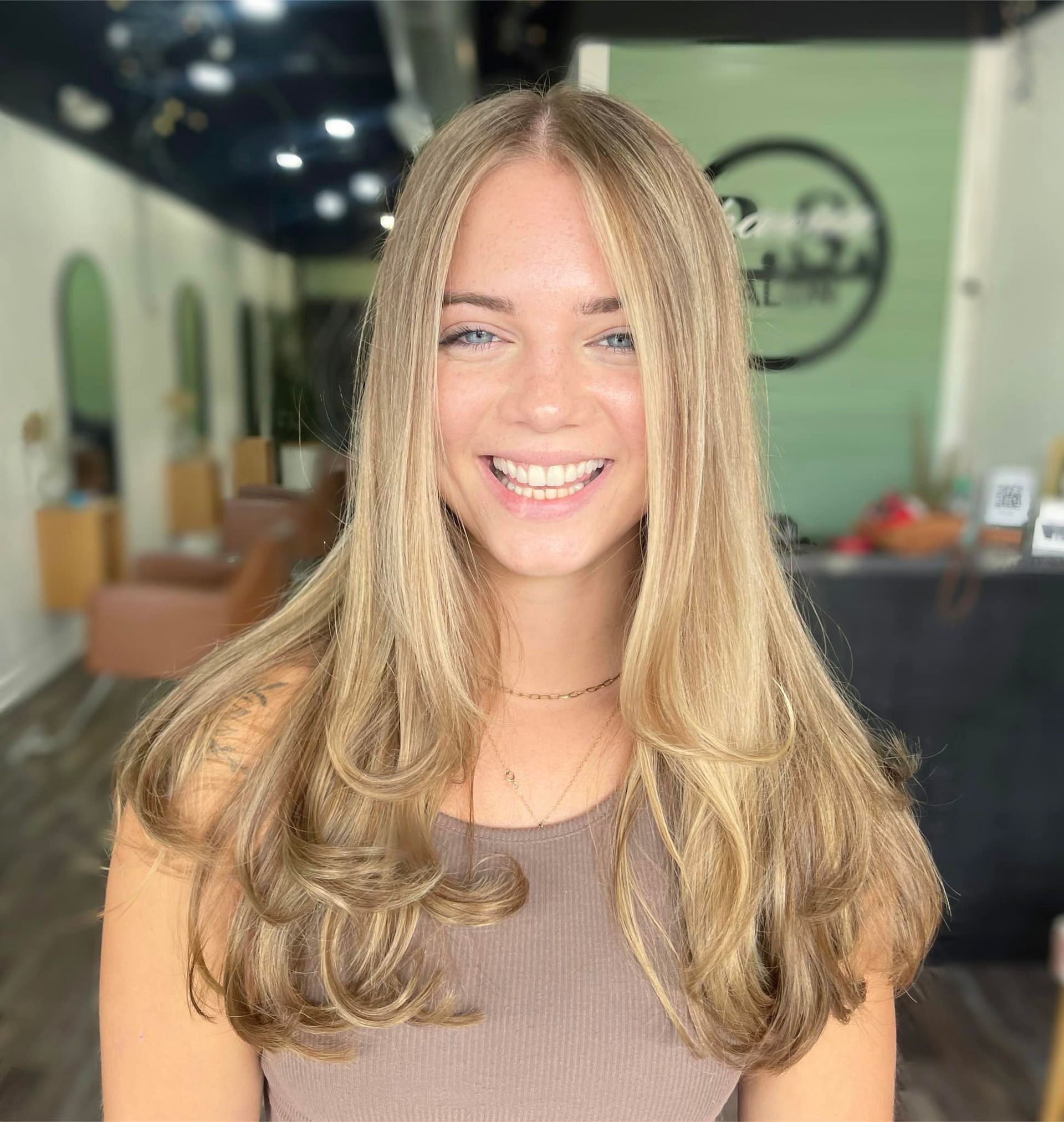 Woman with long blonde hair smiles in a salon.