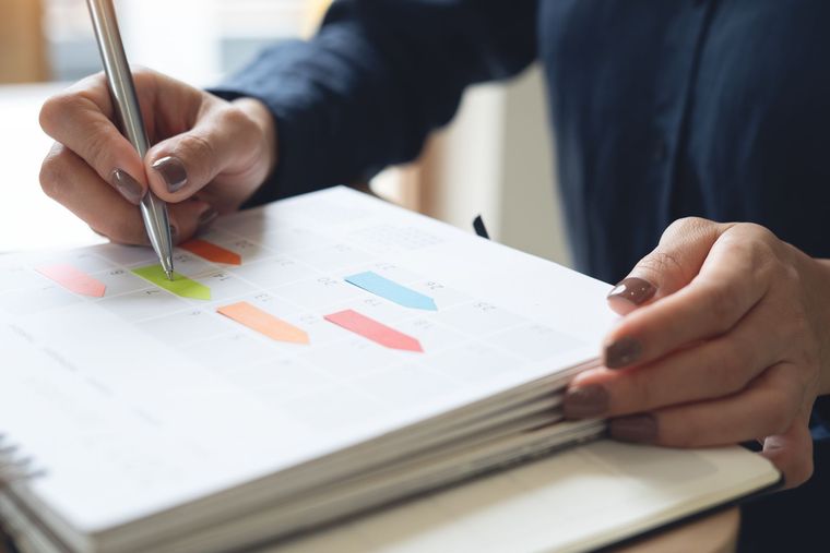Person writing in a notebook, highlighting sections with different colored markers.