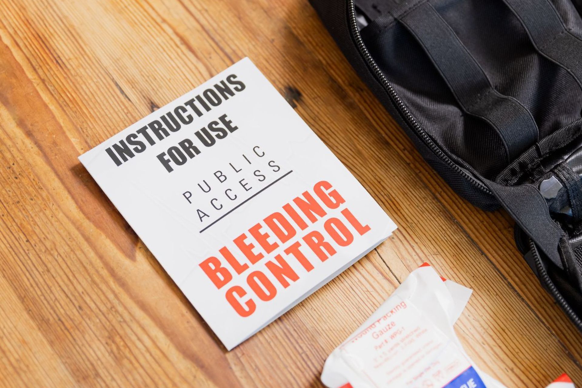 A book titled instructions for use bleeding control is sitting on a wooden table.