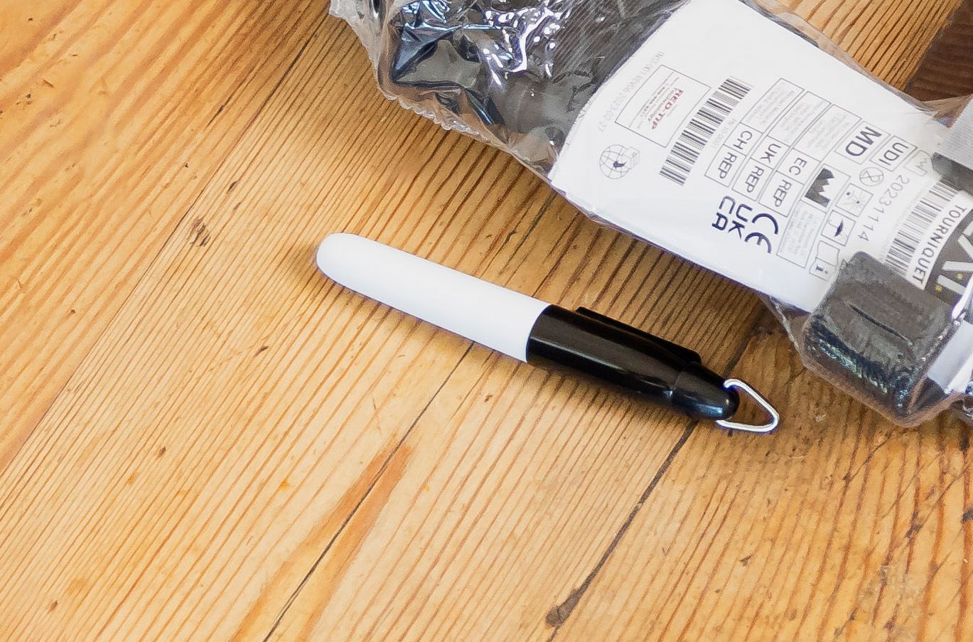 A white marker is laying on a wooden table next to a bag of screws.