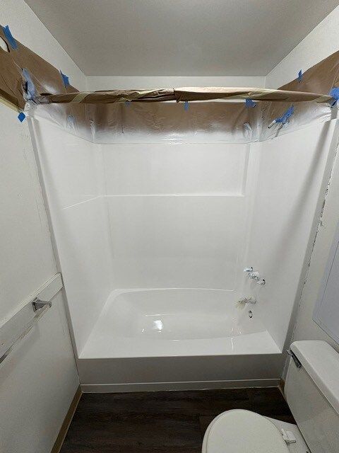 A newly renovated, small bathroom with a white bathtub and toilet.