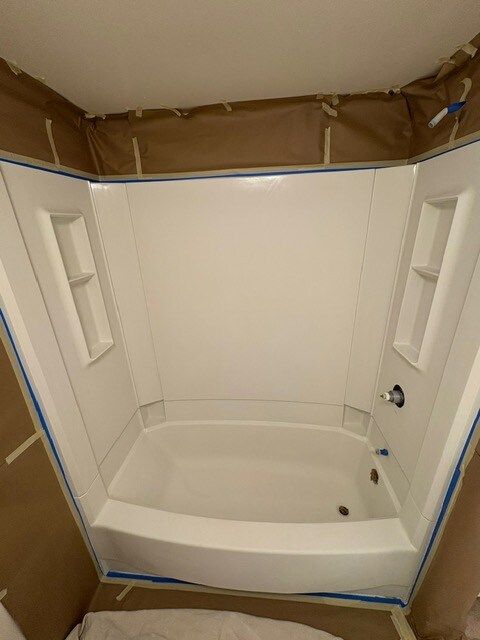 White shower stall with built-in shelves, masked with brown paper and blue tape, ready for painting.