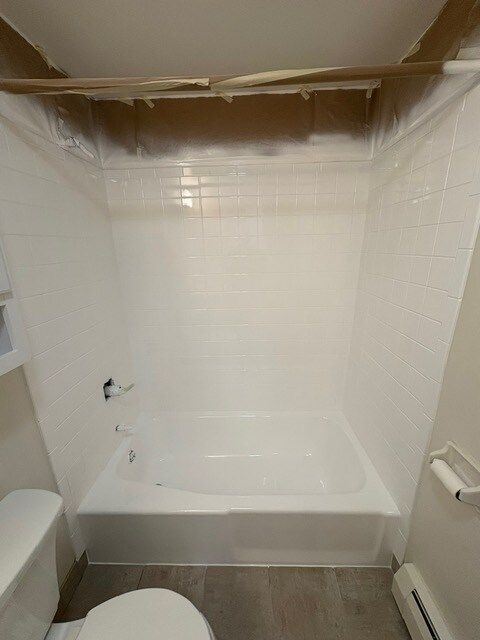 White bathroom with a tub, toilet, and tiled walls. A toilet is on the left and a towel rack is on the right.
