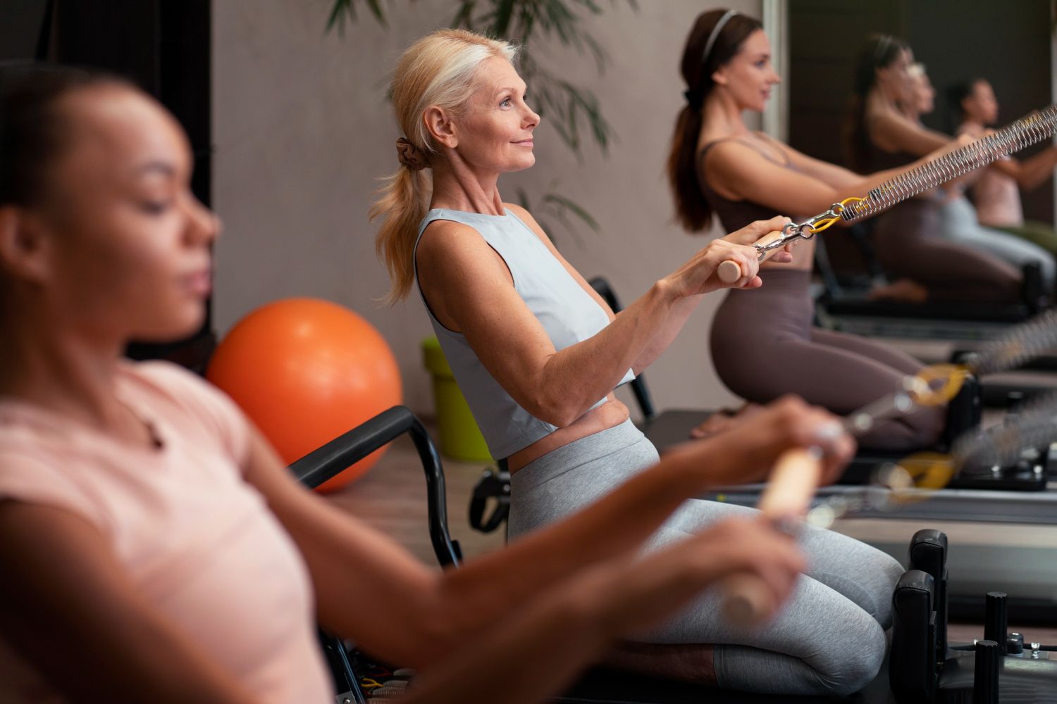 People exercising on rowing machines in a gym, focused on a workout class.