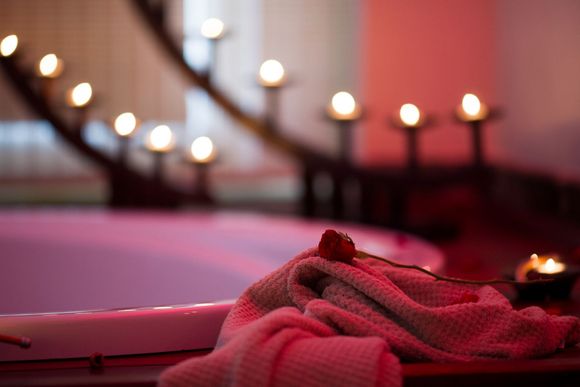 Pink towel and candlelit bathtub in a soft-focus spa setting