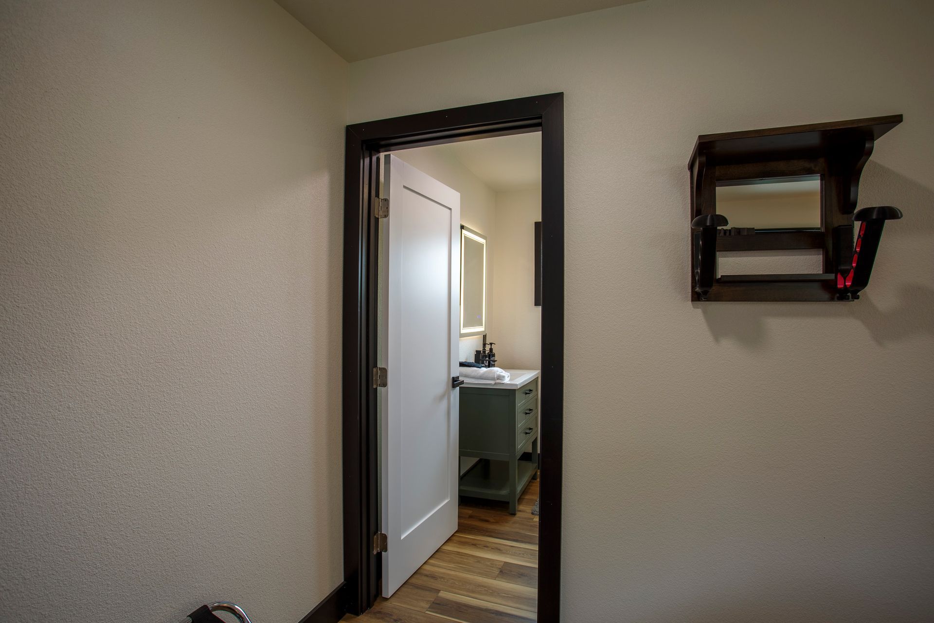 Hallway view into a bathroom with an open door and wall shelf on the right.