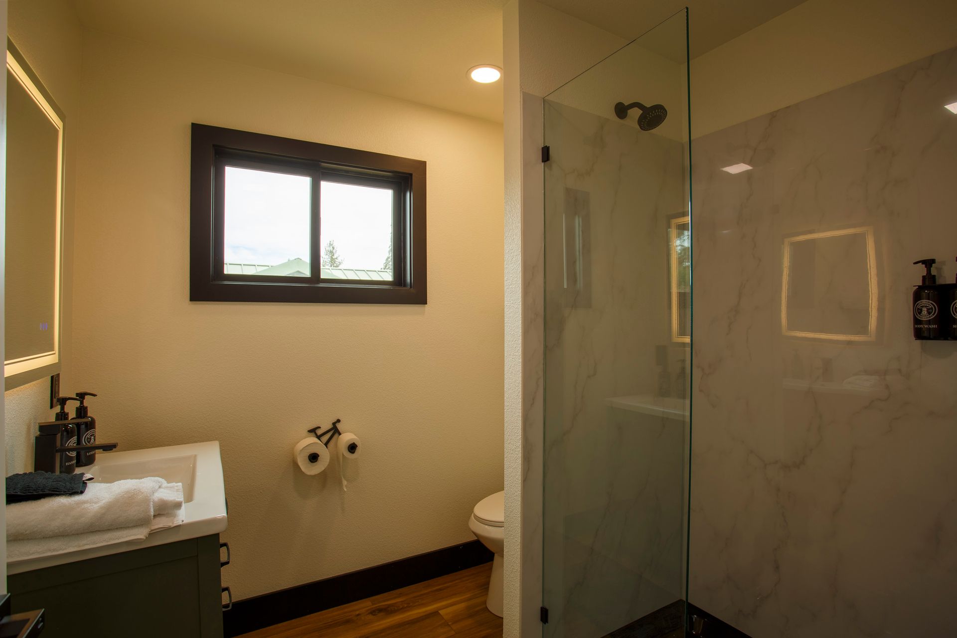 Modern bathroom with sink, toilet, glass shower, and small window