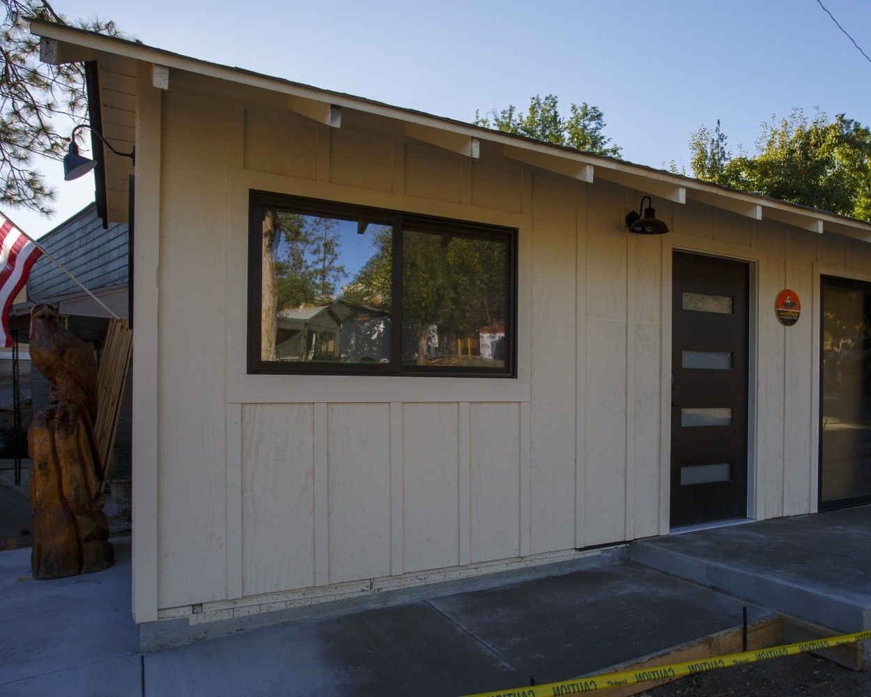 Small beige building exterior with window, dark door, and sidewalk in front