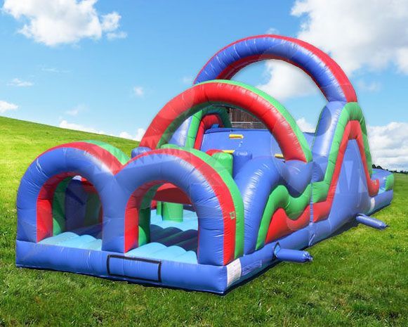 Colorful inflatable obstacle course with red, blue, and green arches on grass under a blue sky