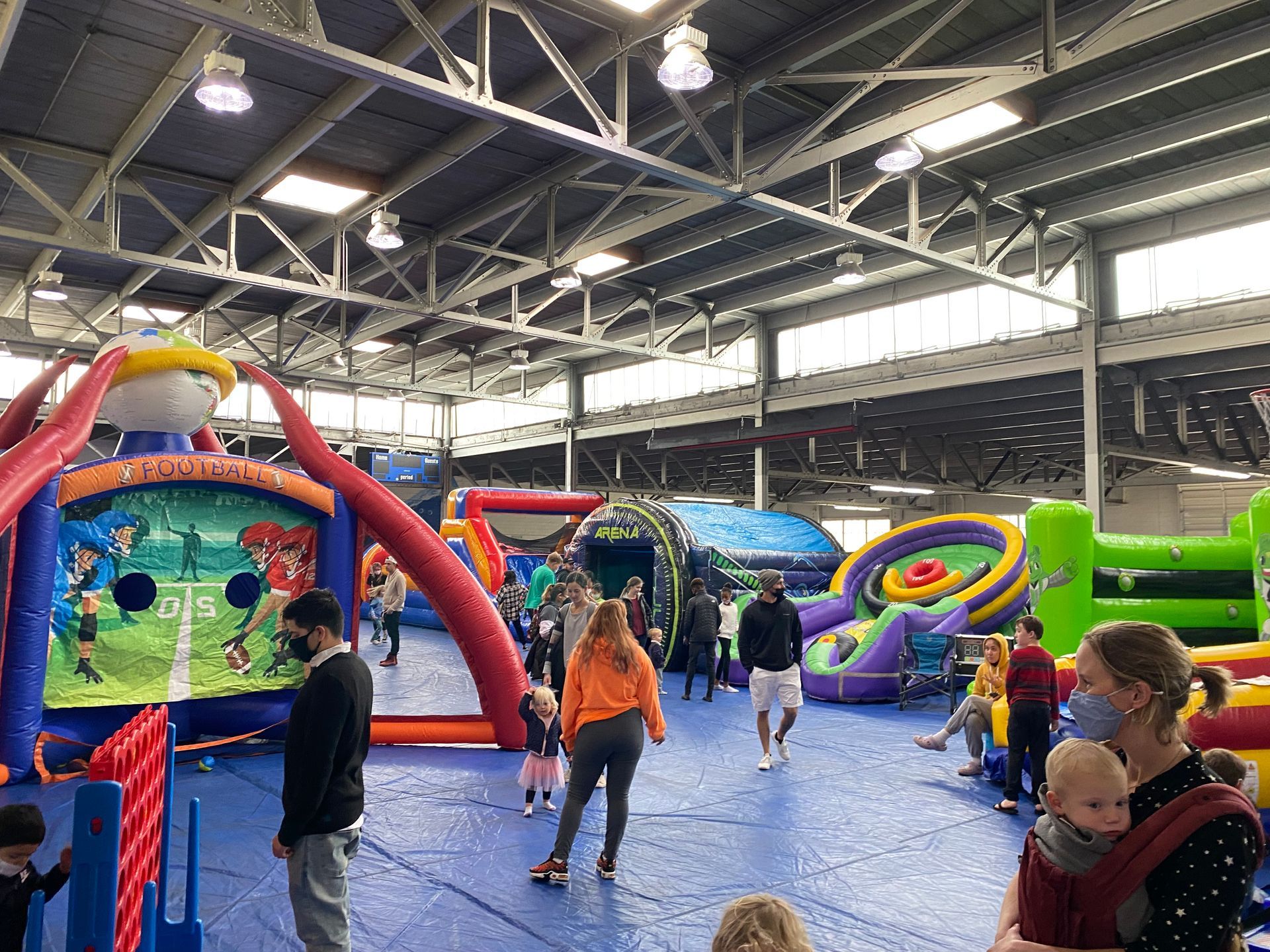 Indoor bounce house play area with colorful inflatable attractions and children playing on a blue mat