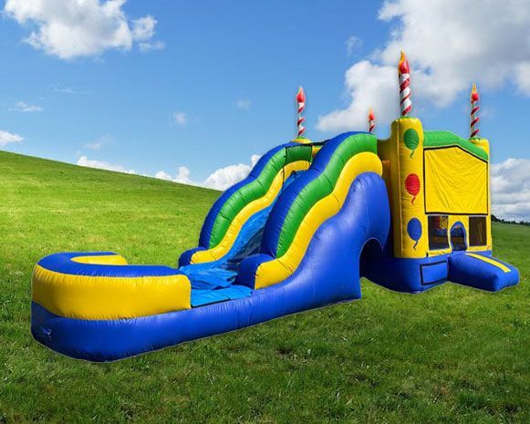 Colorful inflatable bounce house with slide on a grassy hill under a blue sky