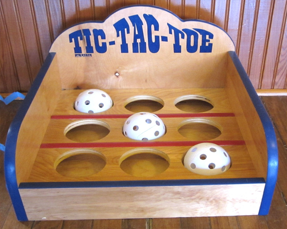 Wooden tic-tac-toe game board with three white balls on a slotted surface