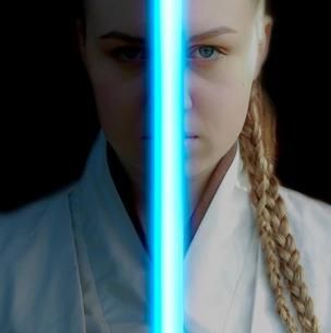 Split portrait of a person in a white robe, bisected by a glowing blue vertical light on a dark background