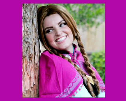 Smiling woman in a pink shawl leaning against a tree outdoors