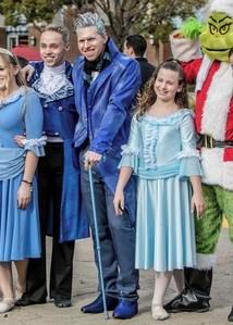 Group in blue outfits posing with the Grinch in an outdoor setting