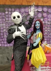 Jack Skellington and Sally stand posing together at a Halloween-themed backdrop.