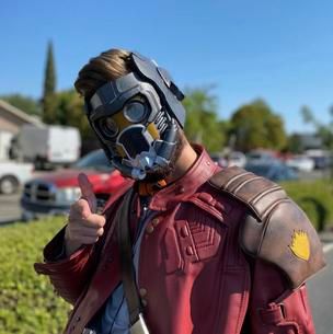 Person in a Star-Lord costume gives a thumbs-up outdoors on a sunny day.