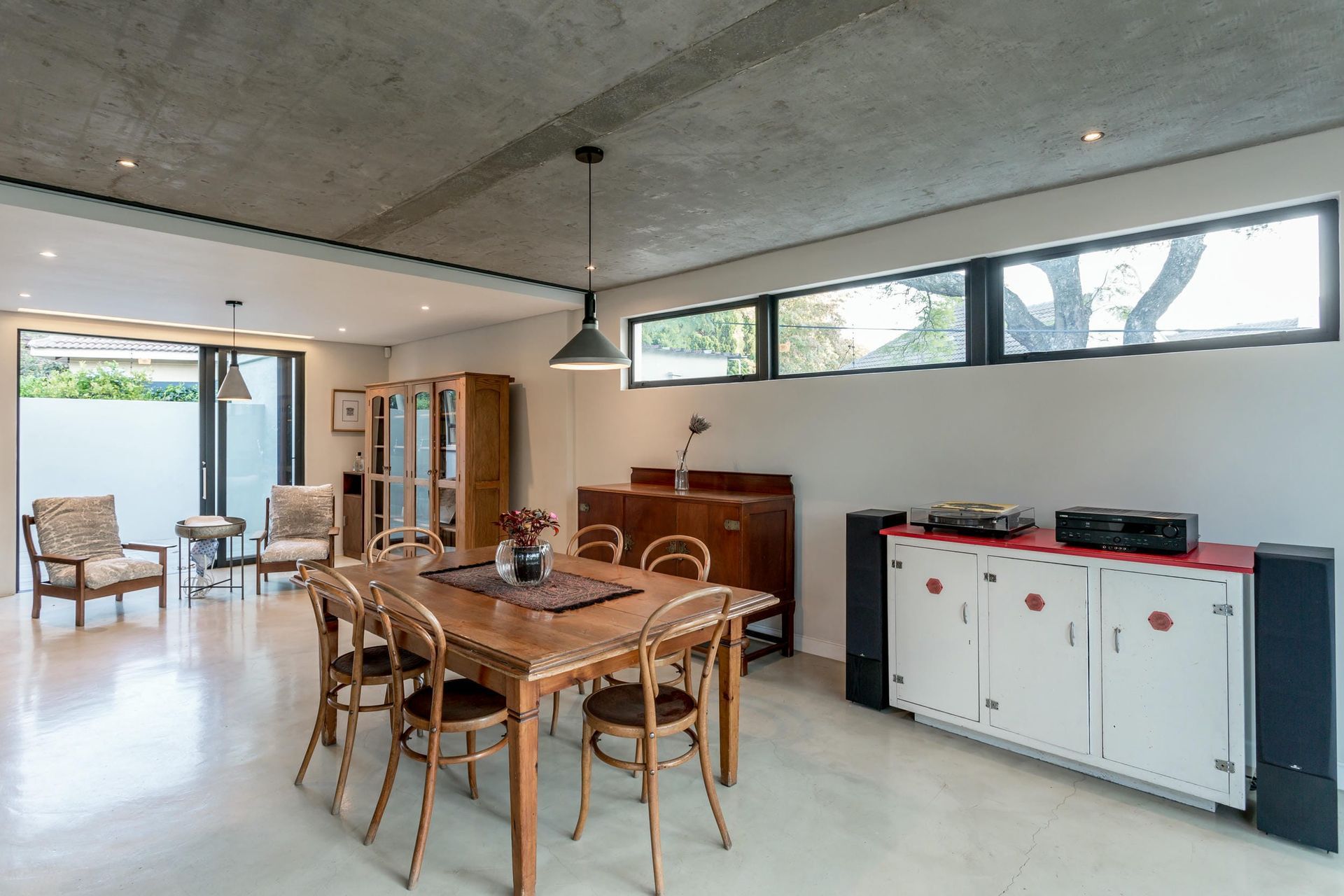 A dining room with a table and chairs and a dresser.