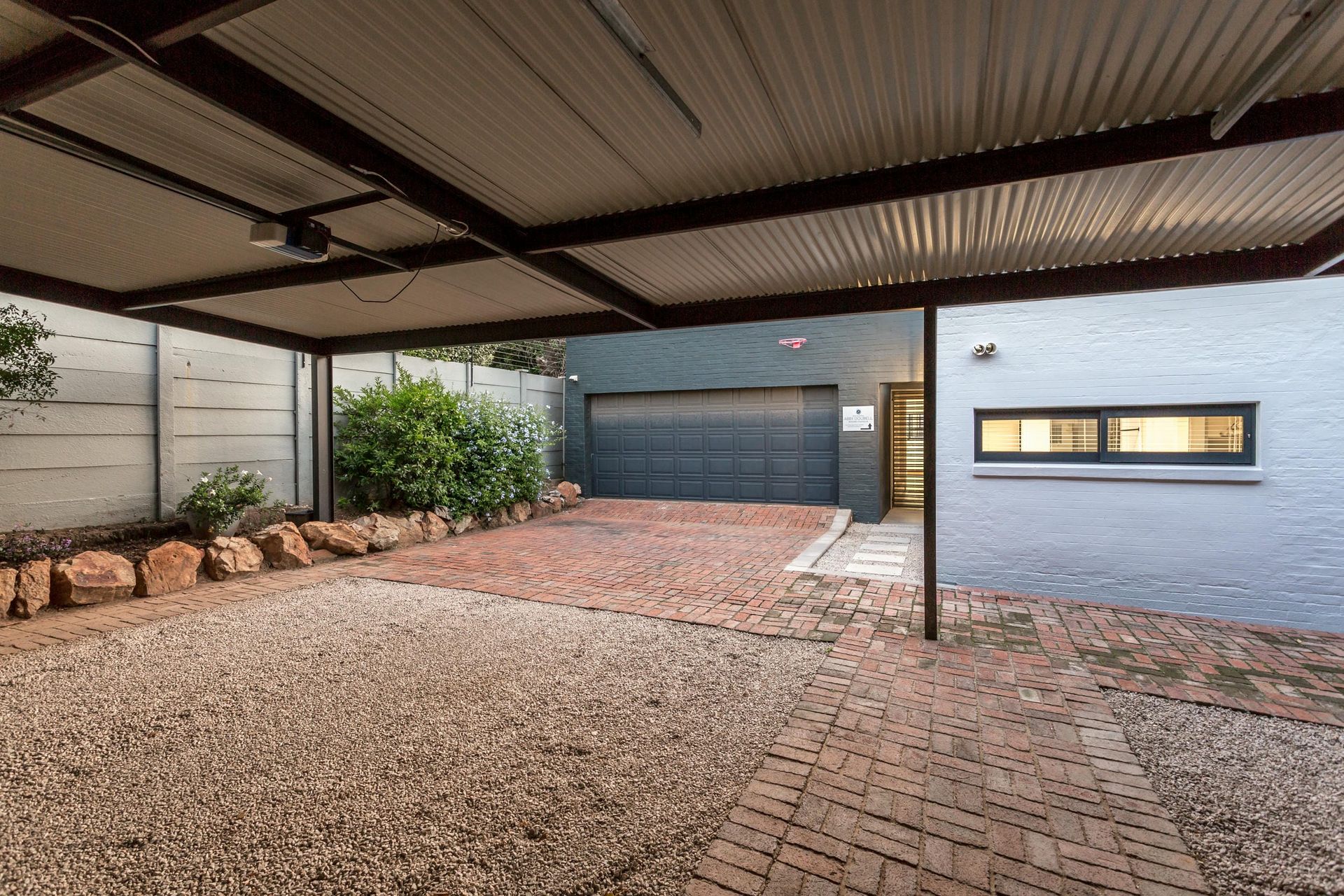 A garage with a canopy over it and a brick driveway